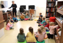 Przedszkolaki z kwiatem w bibliotece